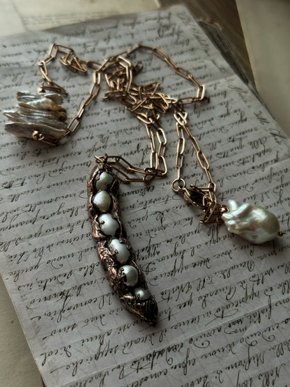 Collana lunga con ciondolo baccello in rame e sei perle d'acqua dolce, appoggiata su pagina di libro antico – Ebbijoux