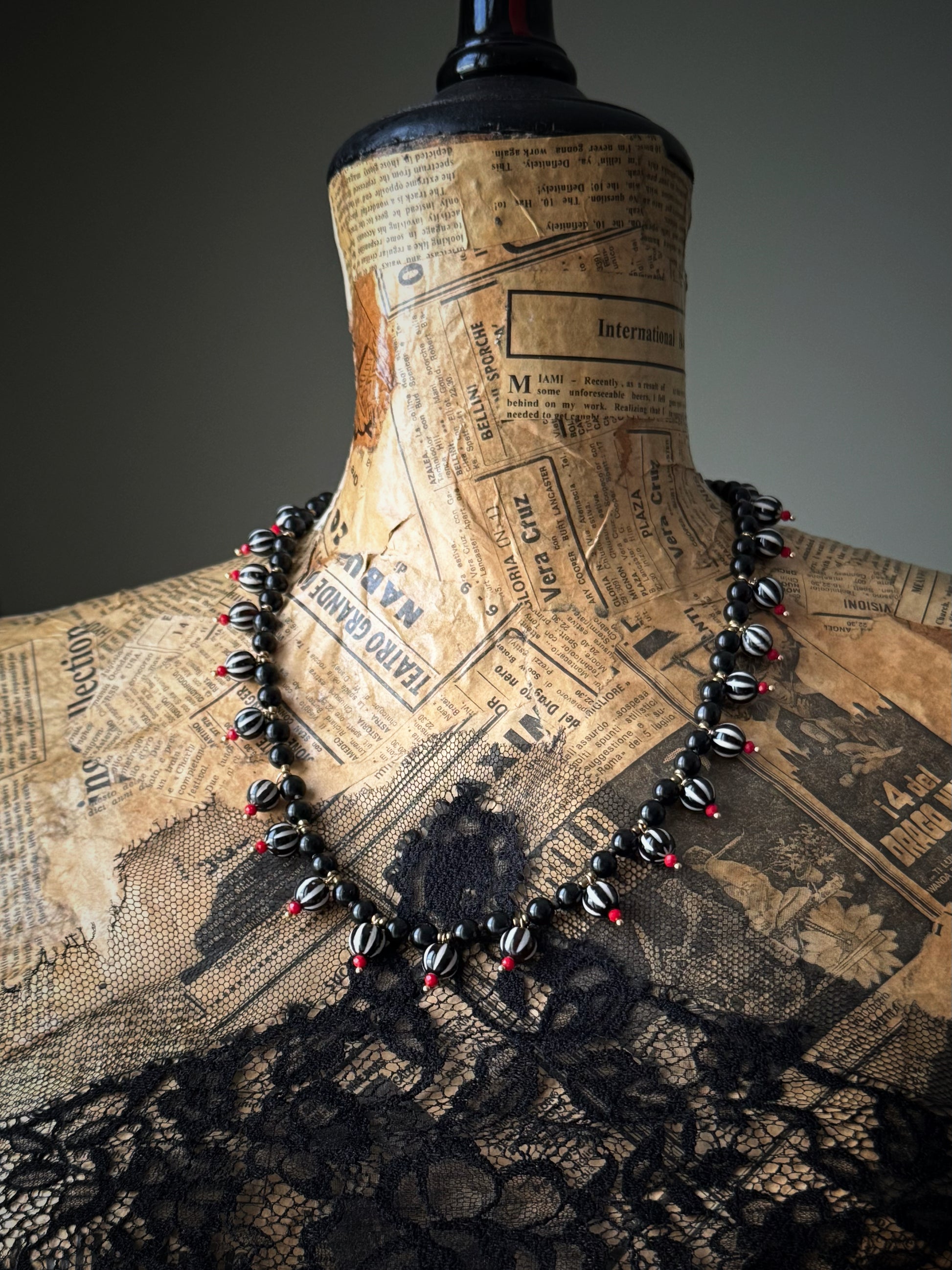 Collana indossata sul manichino vintage con giornale e pizzo