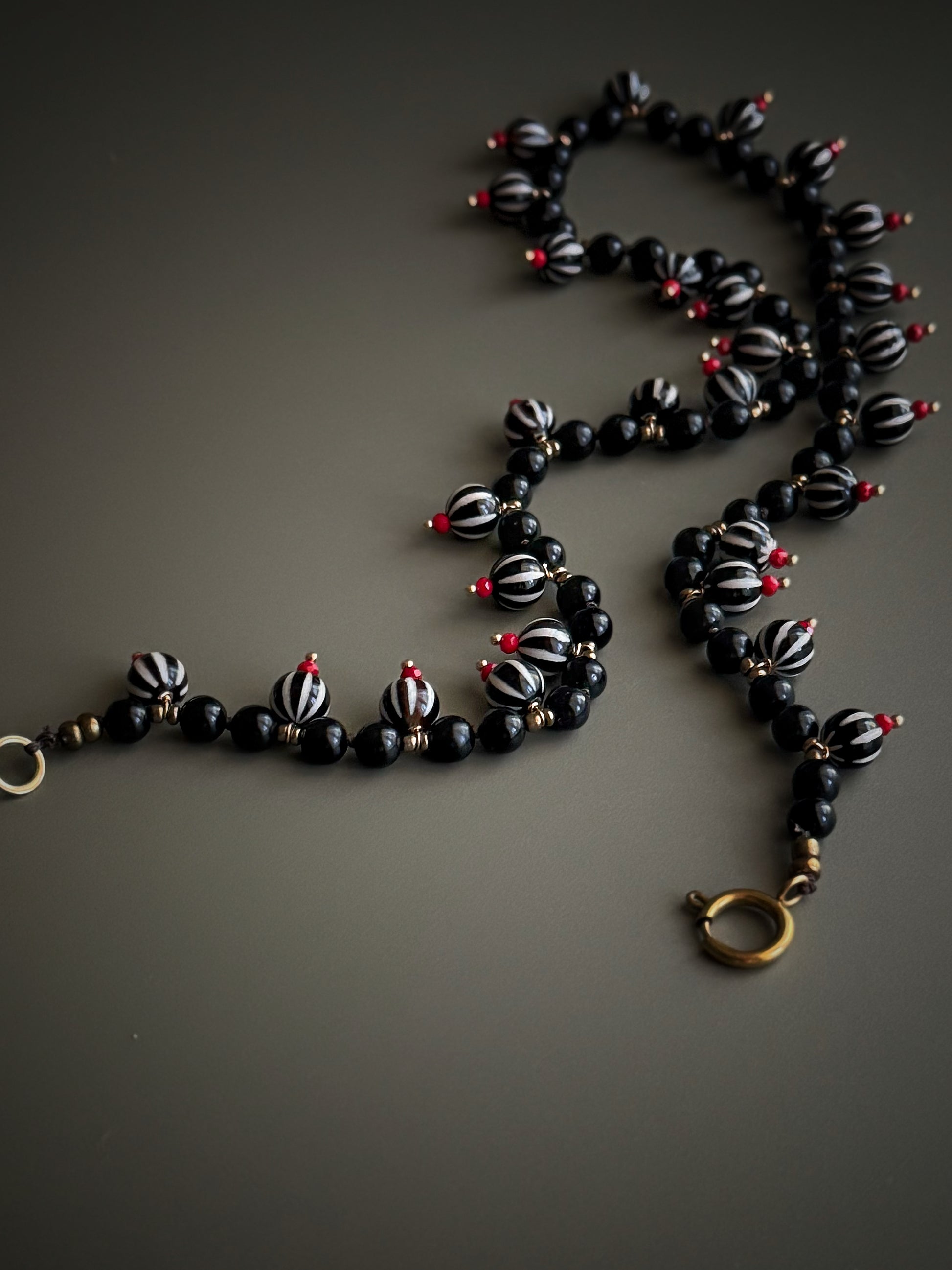 Dettaglio dei ciondoli in Agata Dzi e perle di Ossidiana con vetro rosso e chiusura placcata oro – Ebbijoux