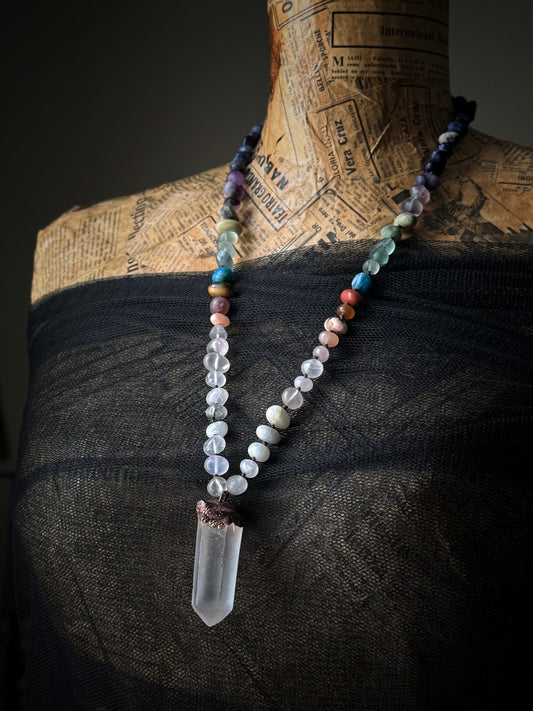 Collana lunga in pietre naturali multicolore con punta di quarzo ialino indossata su manichino vintage con pizzo nero – Ebbijoux