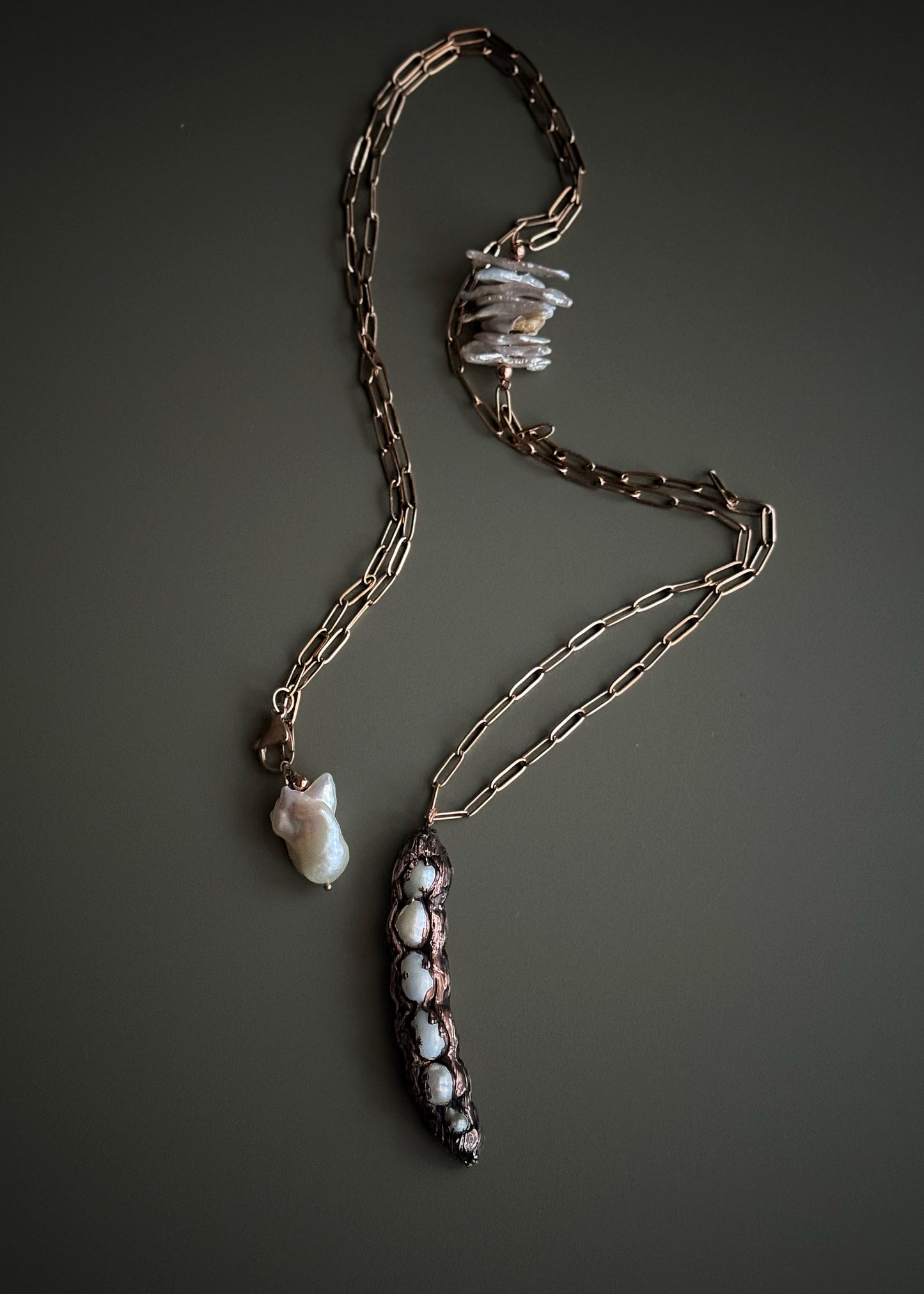 Collana lunga con baccello in rame e perle barocche chips tenuta in mano, dettaglio inserto laterale e chiusura con perla barocca – Ebbijoux