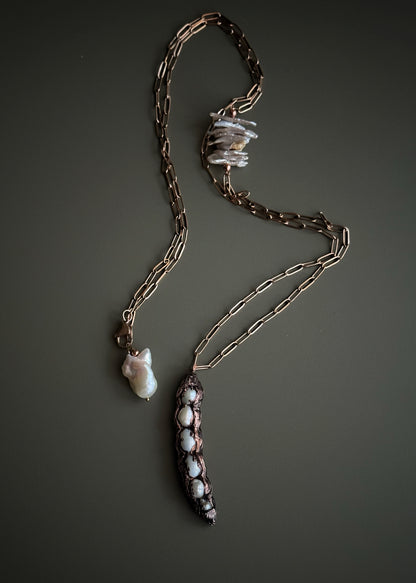 Collana lunga con baccello in rame e perle barocche chips tenuta in mano, dettaglio inserto laterale e chiusura con perla barocca – Ebbijoux