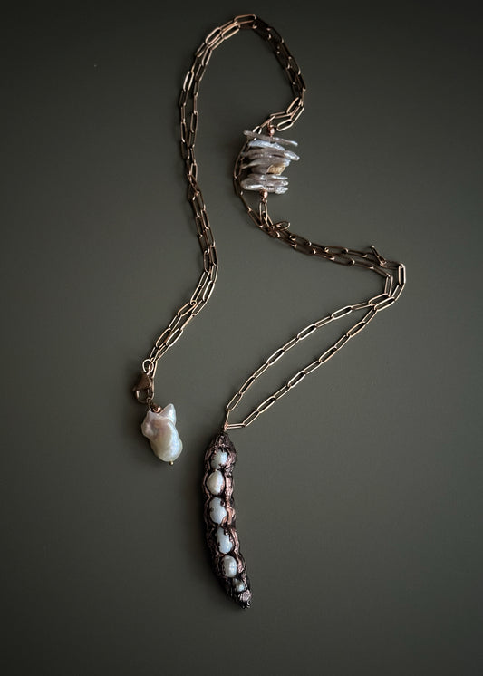 Collana lunga con baccello in rame e perle barocche chips tenuta in mano, dettaglio inserto laterale e chiusura con perla barocca – Ebbijoux
